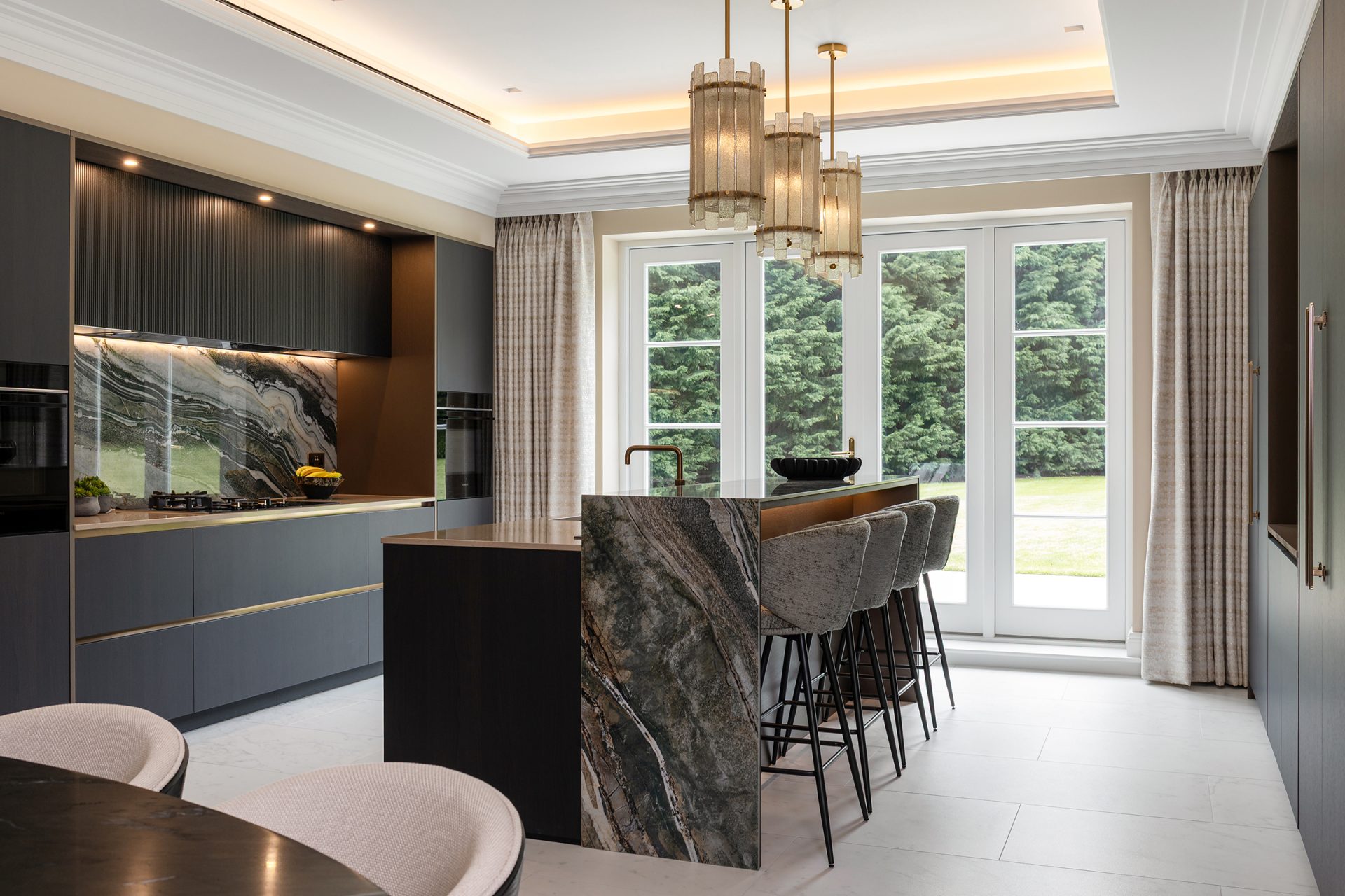 black moody bespoke modern kitchen with island and natural stone breakfast bar in luxurious home