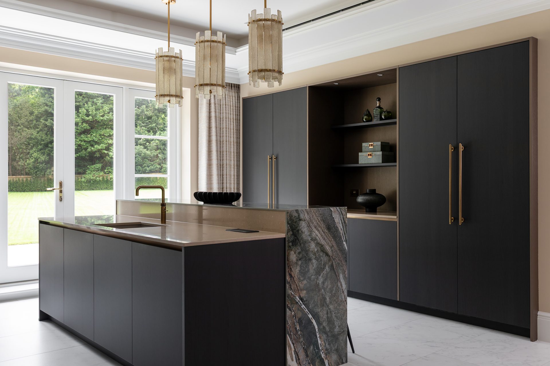 a dark kitchen with bespoke details, an island with stone breakfast bar, open shelving and bronze accents