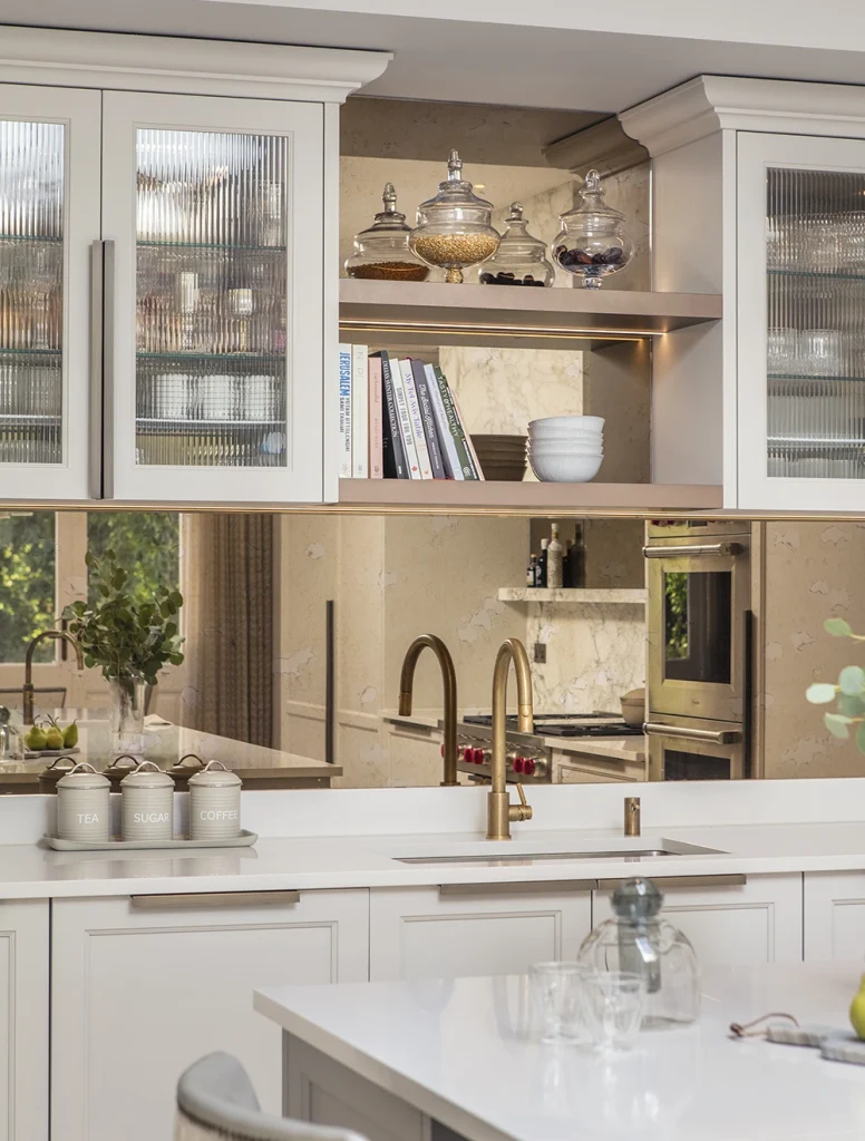 Classic style kitchen with reeded glass glazed wall cabinets and open shelving with antique mirror and brass tap