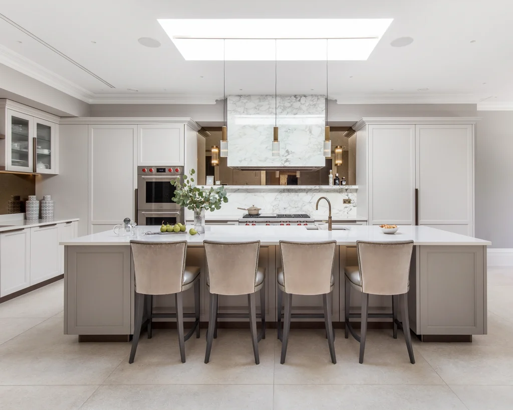 Luxurious contemporary classic kitchen with light neutral handpainted cabinets, modern feature stone-clad cooker hood, bronze mirror splashback and Subzero Wolf appliances